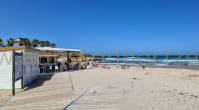 Strandbar Playa Flamenca op zandstrand met mensen aan tafel.
