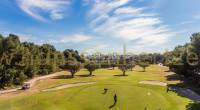 Campo de golf de Villamartín con árboles y jugadores de golf.