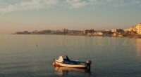 Kleine boot op kalm water met de stad Torrevieja op de achtergrond.