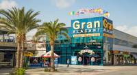 Centro comercial Gran Alacant con palmeras y banderas.