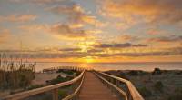 Een houten loopbrug die leidt naar het strand bij zonsondergang in Gran Alacant.